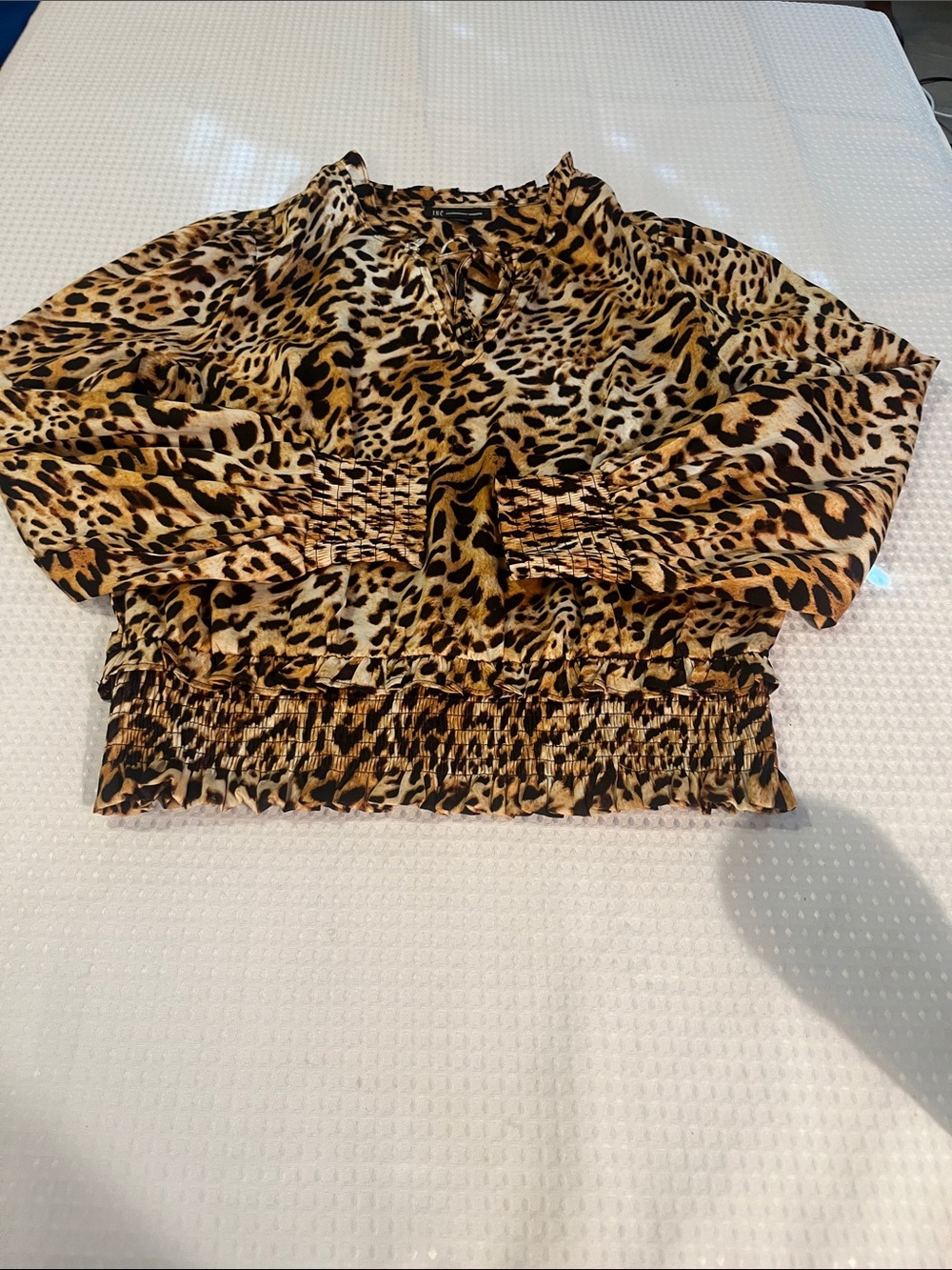 Lightweight leopard-print blouse with a smocked waist. Long sleeves with elastic